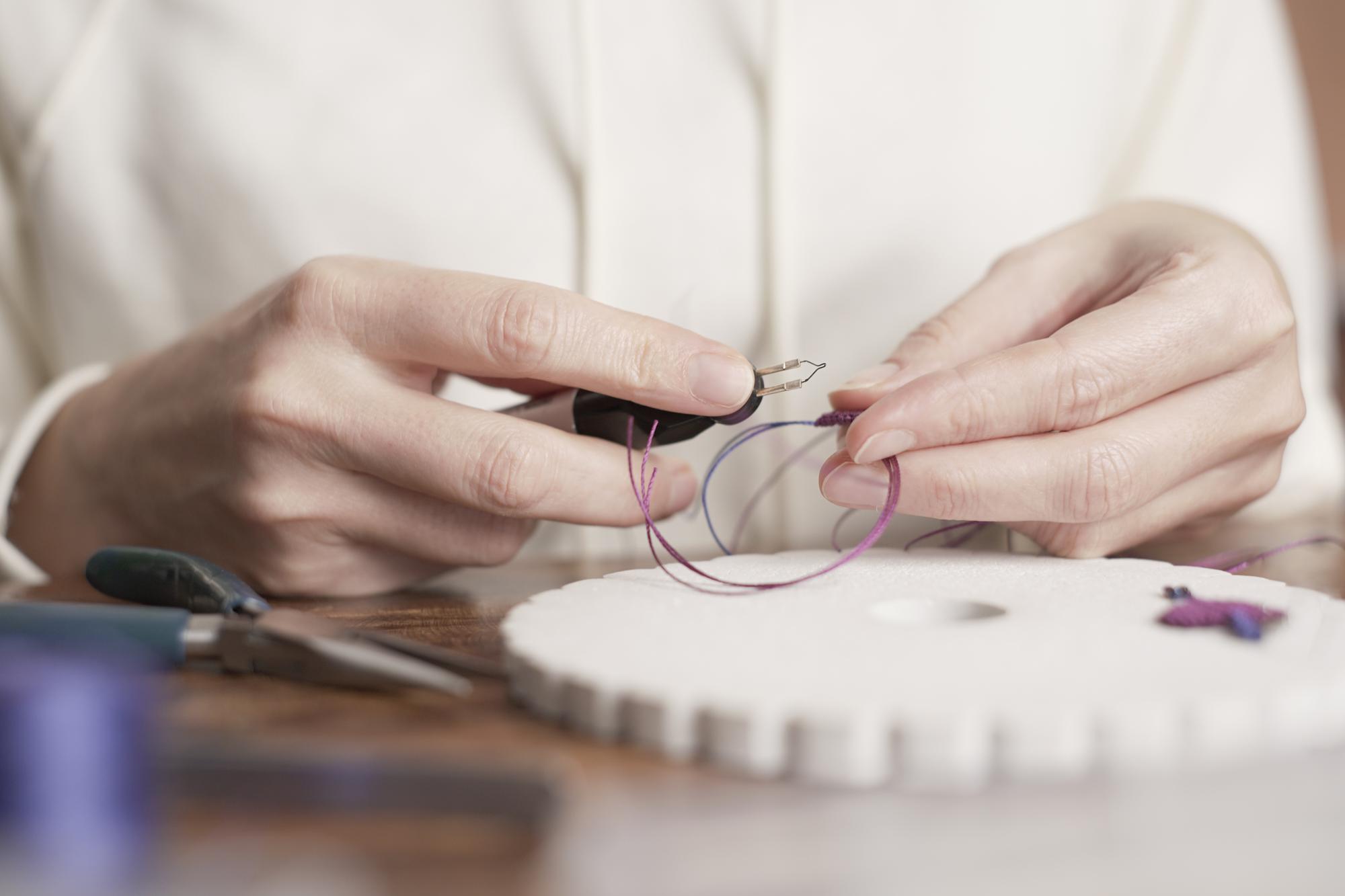 Hand embroiderer at work with magnifier